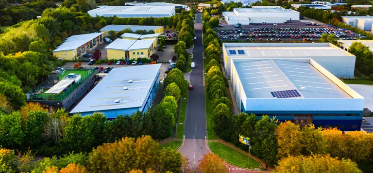Vista aérea de galpões industriais cercados por áreas arborizadas