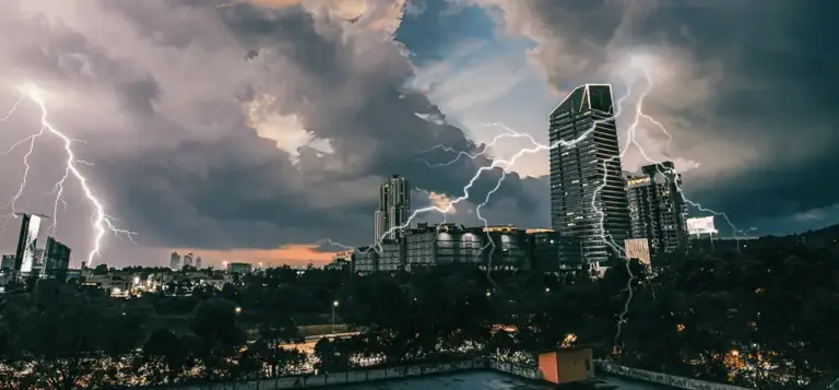Raios cruzam o céu carregado sobre os prédios de uma cidade