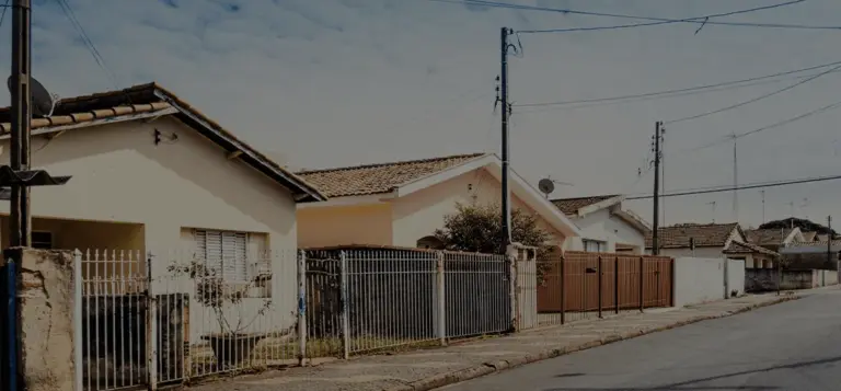 Rua de bairro residencial com casas simples e postes de energia