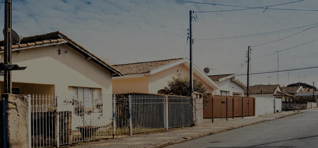 Rua de bairro residencial com casas simples e postes de energia