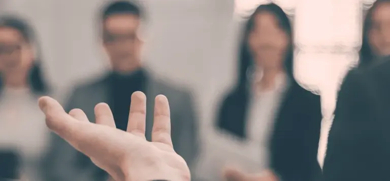 Pessoa gesticula durante uma conversa com um grupo ao fundo