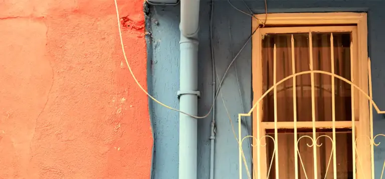 Fachada de uma casa simples com janela gradeada e paredes coloridas