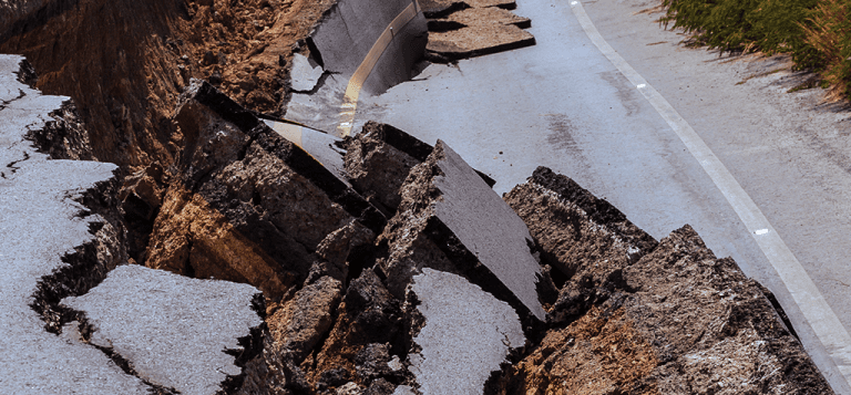 Imagem de uma estrada de asfalto destruída com buracos abertos necessitando de engenharia consultiva em situações de emergência.