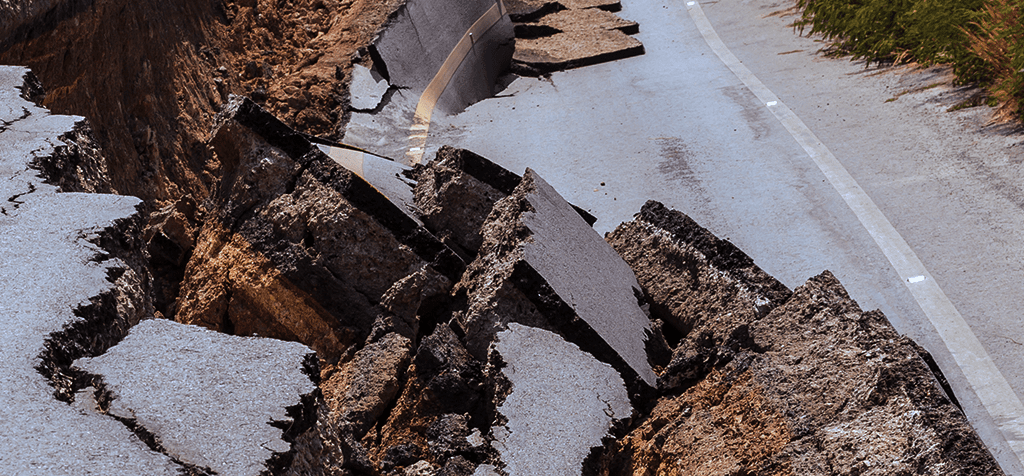 Imagem de uma estrada de asfalto destruída com buracos abertos necessitando de engenharia consultiva em situações de emergência.